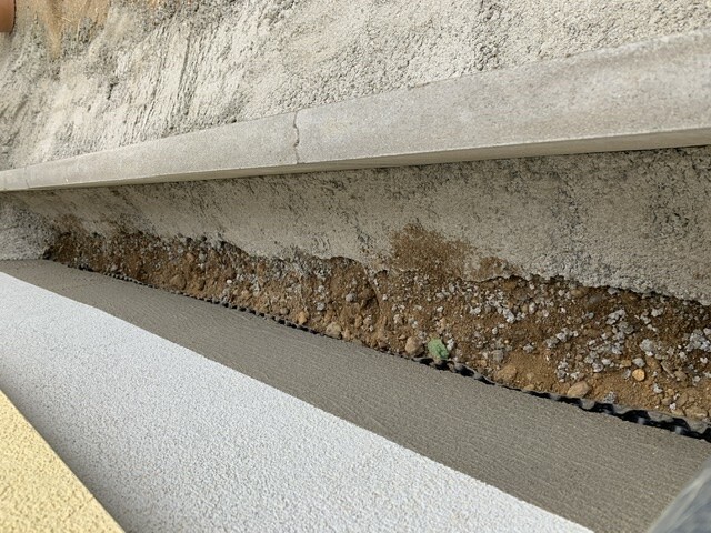 Bau-Szene: Betonbalken über Erdreich mit Kies, darunter glatte Betonplatte.
