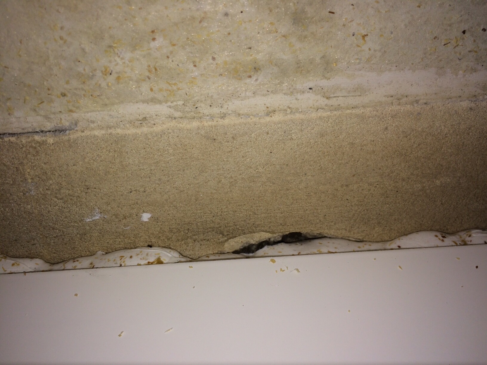 Nahaufnahme einer rauen Kellerfundament-Betonwand am Bodenbereich