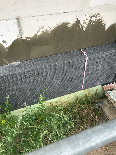 Außenwand mit Dichtbahn am Fundament, Feuchtigkeitsschutz im Rohbau sichtbar