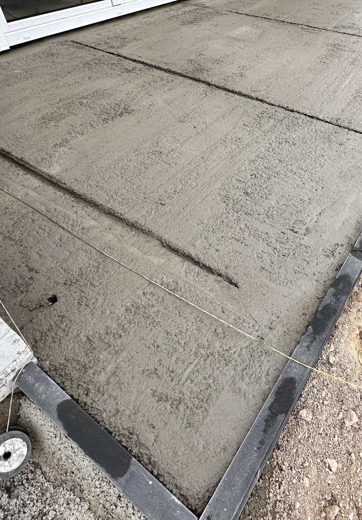 Frisch gegossene Betonbodenplatte mit Schalung und Ausrichtungsleine.