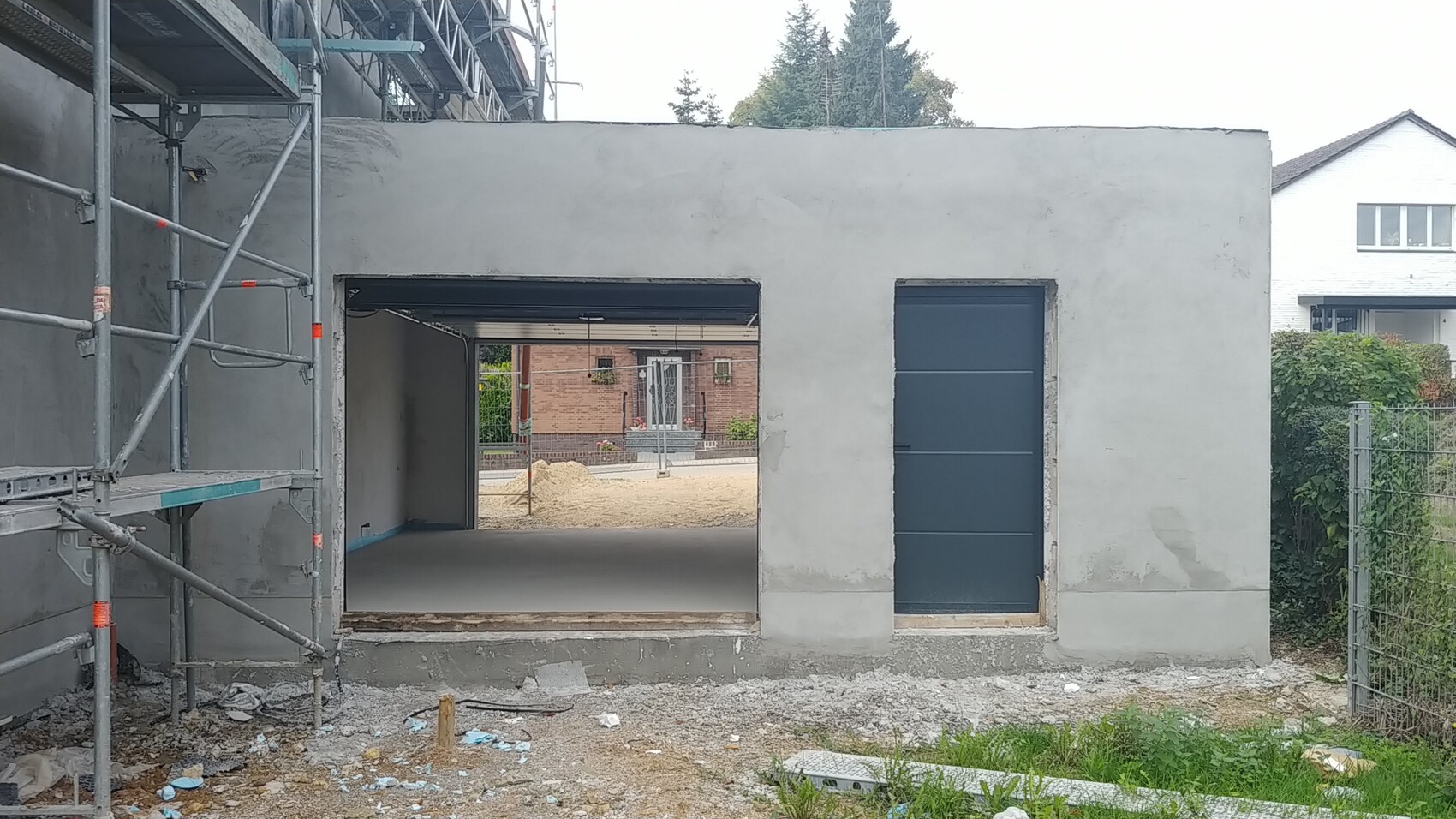 Baustelle mit Rohbau, Geruest und offenem Durchgang am Boden, Bauabfaelle sichtbar