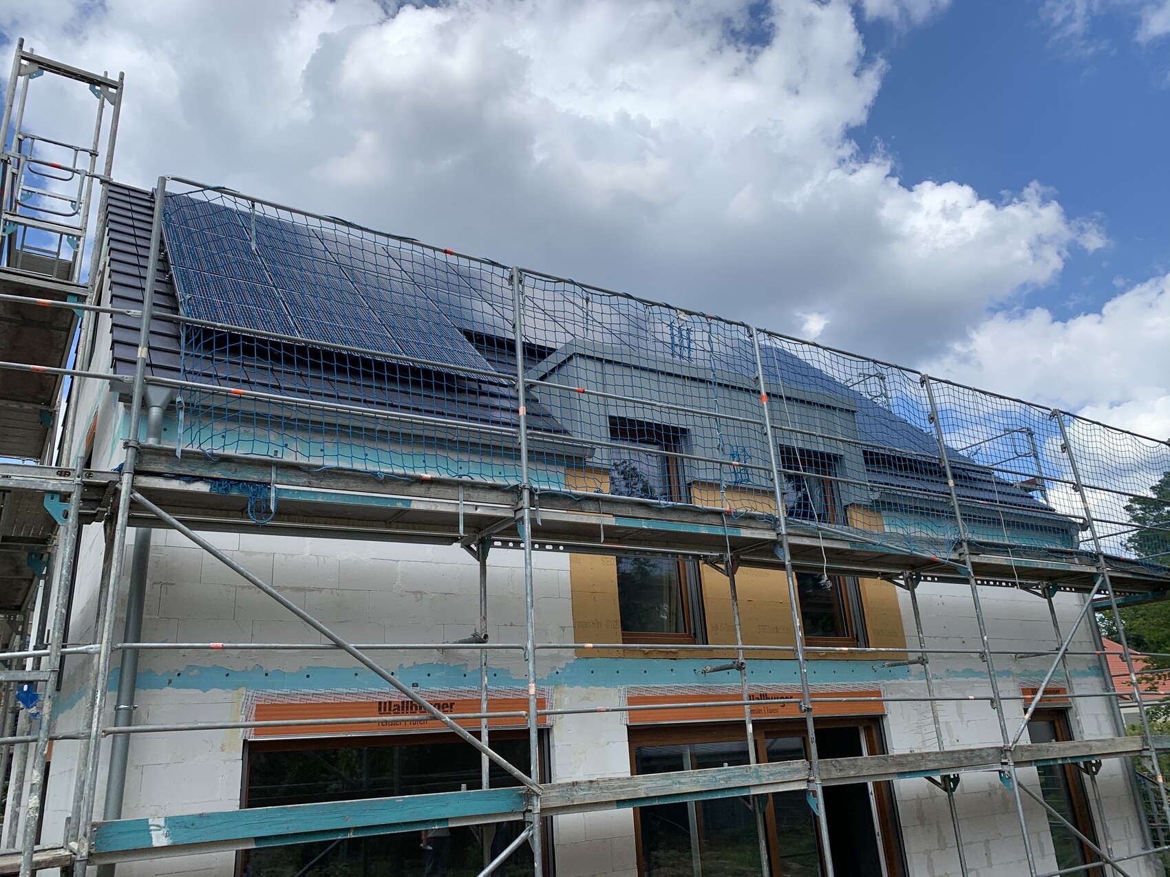 Gerüst um Bauhaus im Rohbau, Dach mit Solarpanels, Bauarbeiten sichtbar
