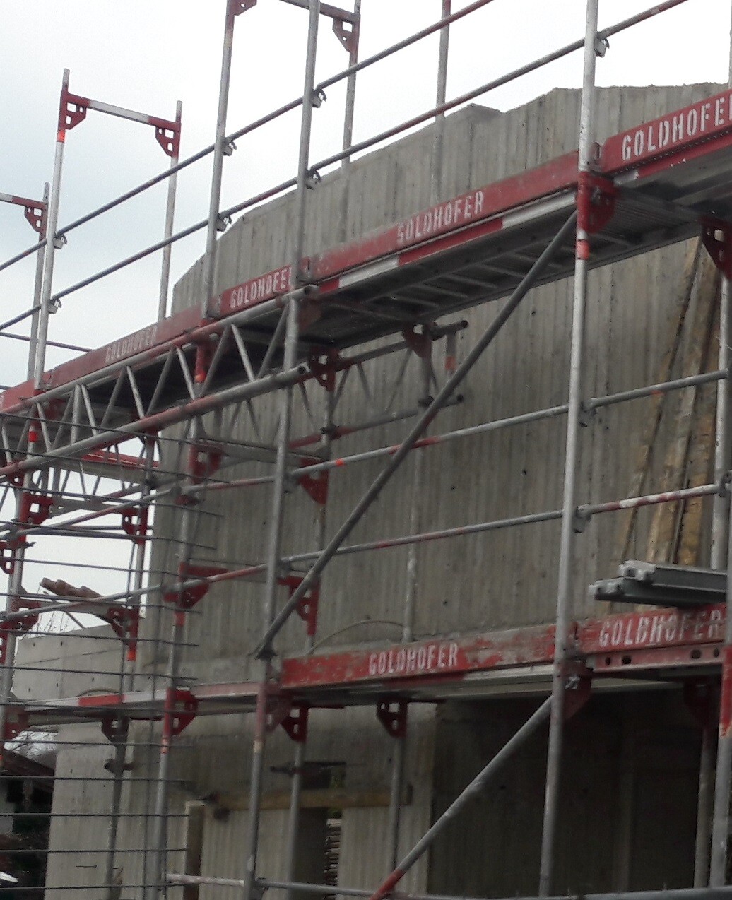 Baustellengerüst aus Stahl vor einer Betonwand; rotes Gerüst mit Goldhofer-Beschriftung.