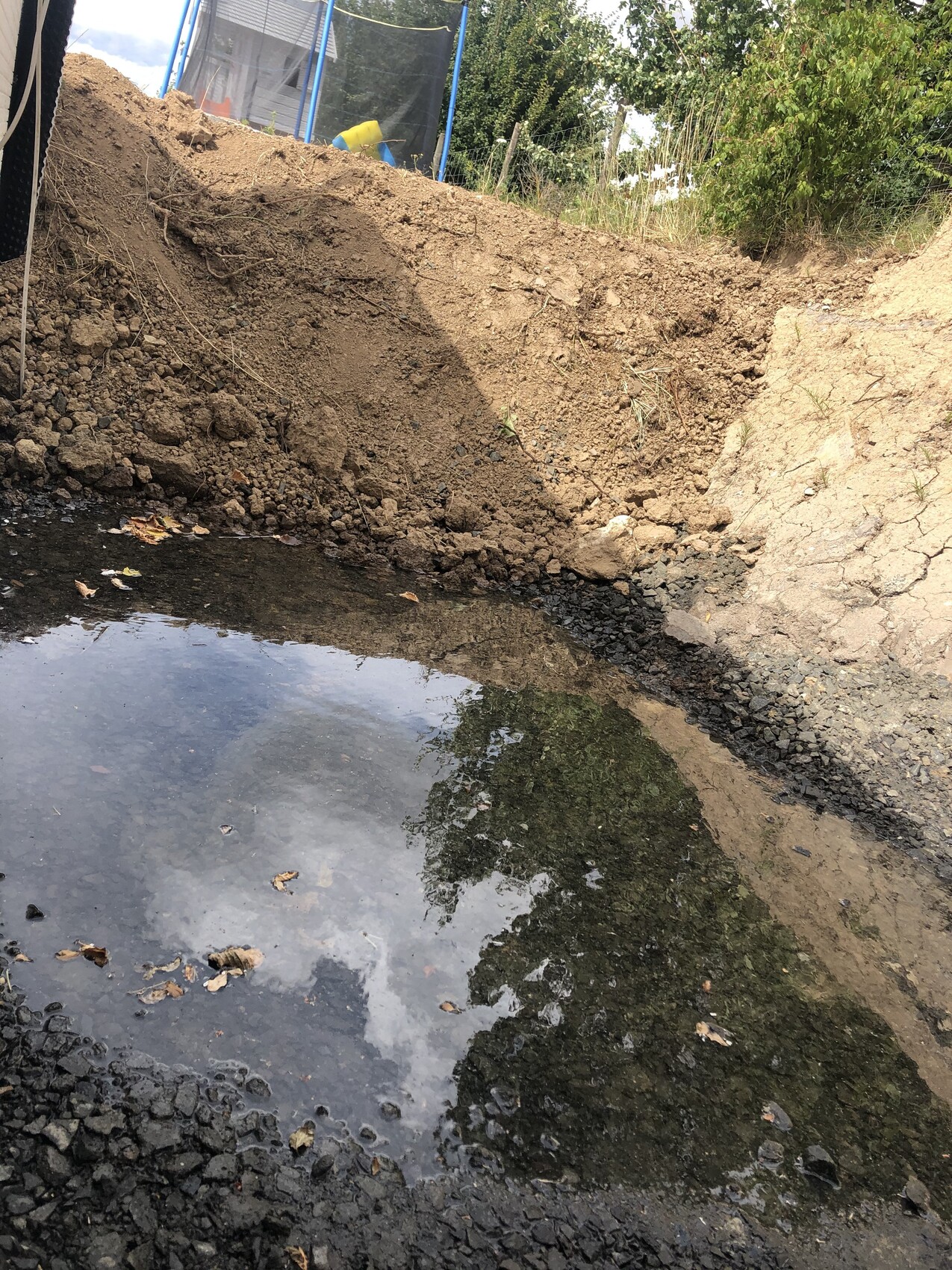 Erdaushub und Wasserpfütze in einer Baugrube während der Rohbauarbeiten