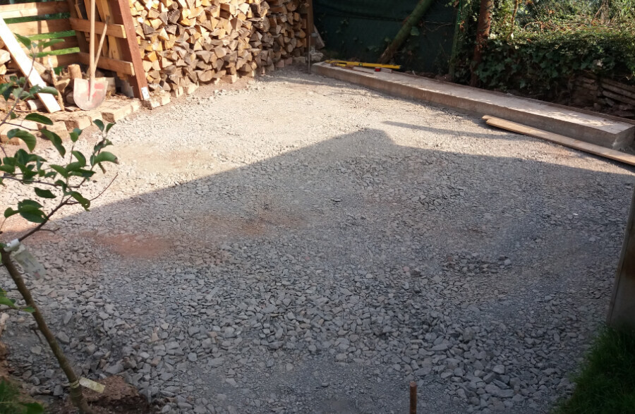 Baustelle mit Kiesuntergrund, Holzstapeln und Bauholz am Rand