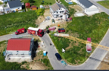 Luftaufnahme eines Bauplatzes mit Rohbau, Kran und Baufahrzeugen