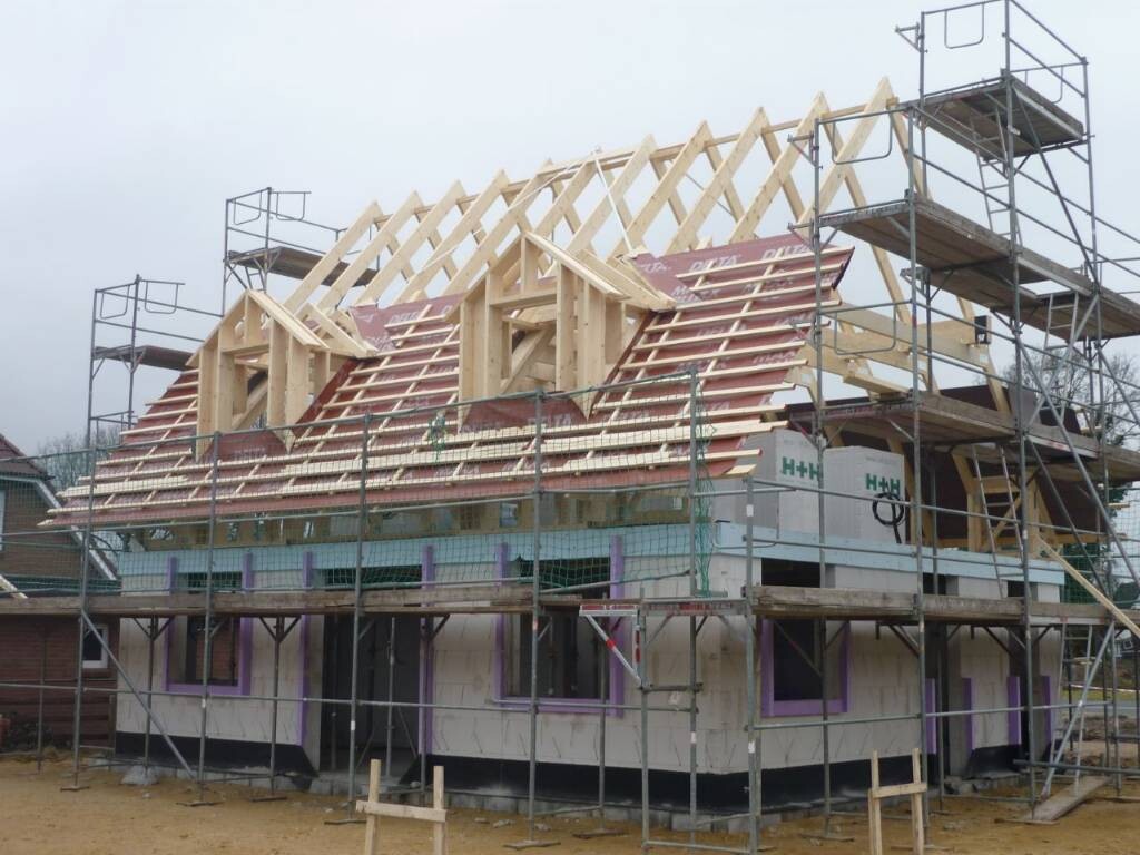 Hausbaustelle: Holz-Dachkonstruktion auf Gerüst umrahmt, Rohbau des Hauses.