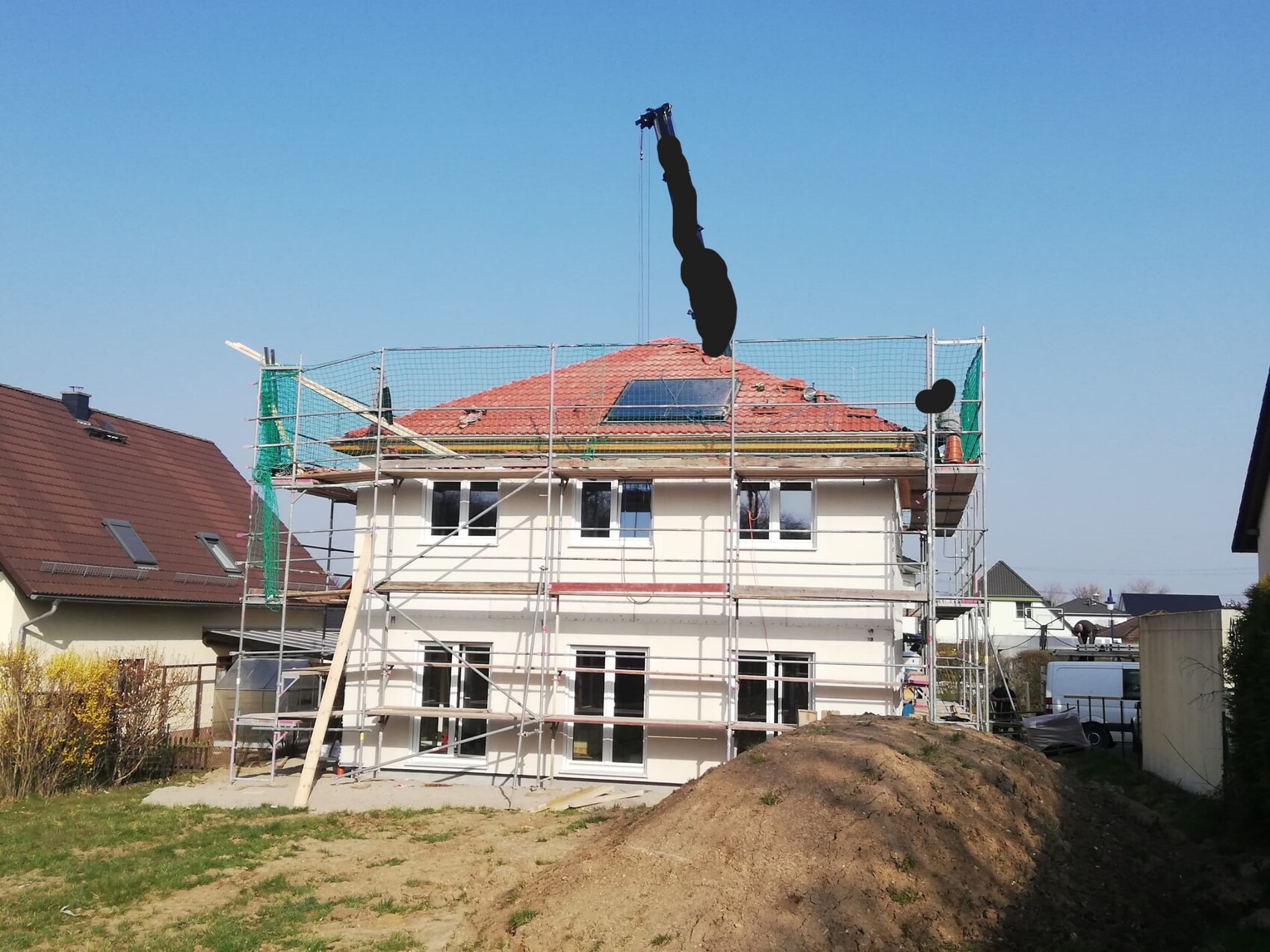 Zweistöckiges Haus mit Gerüst und Kran, Erdarbeiten vor dem Gebäude.