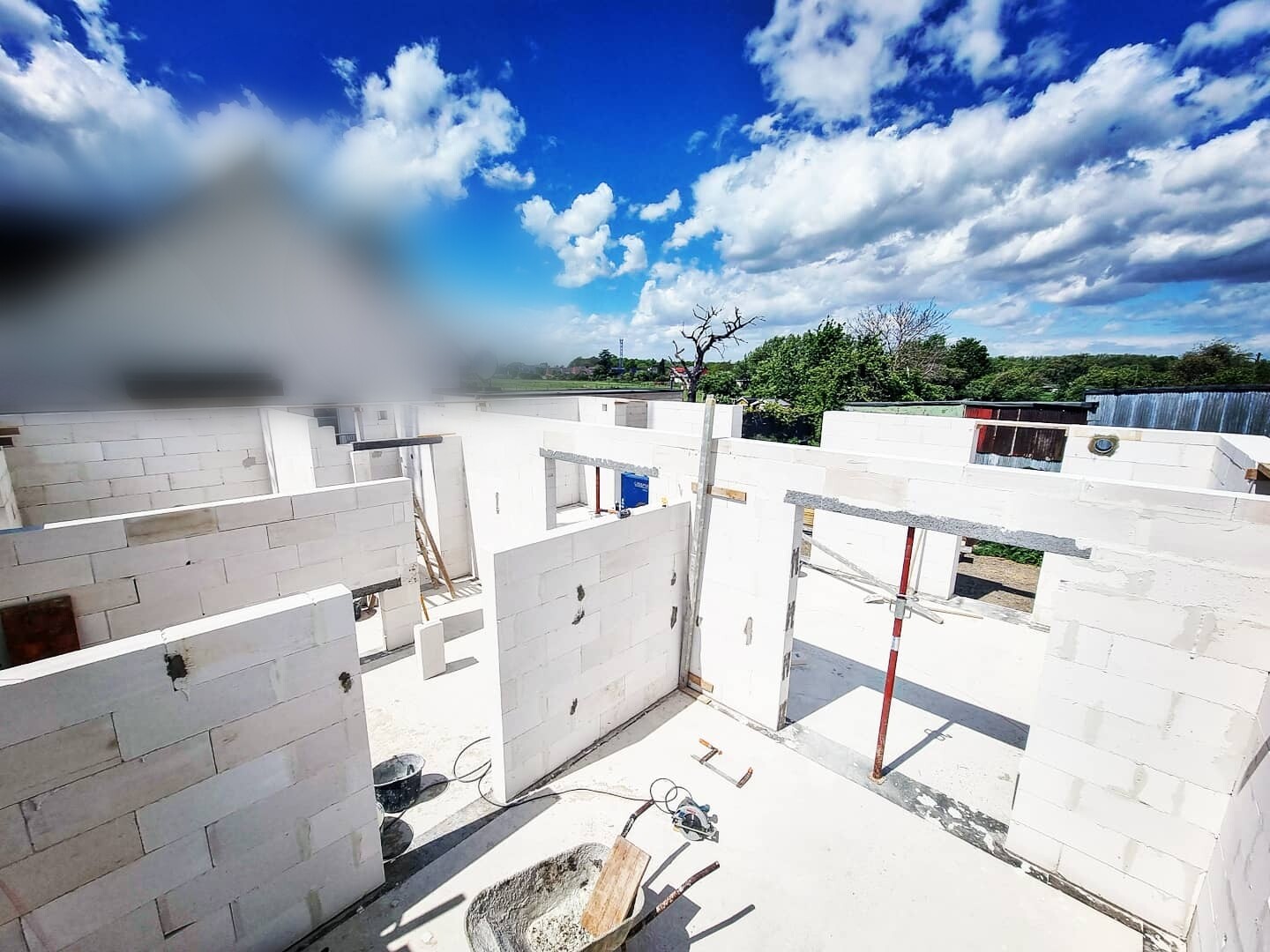 Unfertiges Gebäude aus weißen Betonblöcken auf Baustelle; blauer Himmel und Wolken im Hintergrund.