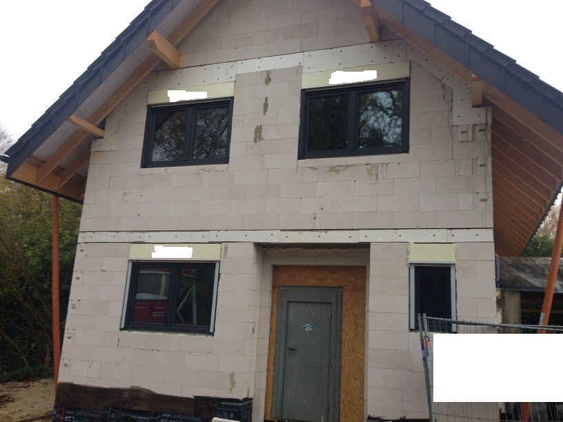 Unfertiges zweistöckiges Haus im Rohbau mit Dach, Fenstern und Tür.