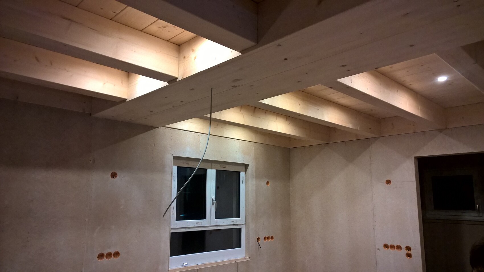 Unbearbeiteter Innenraum mit sichtbaren Holzbalkendecken, Fenster und Wandlöchern