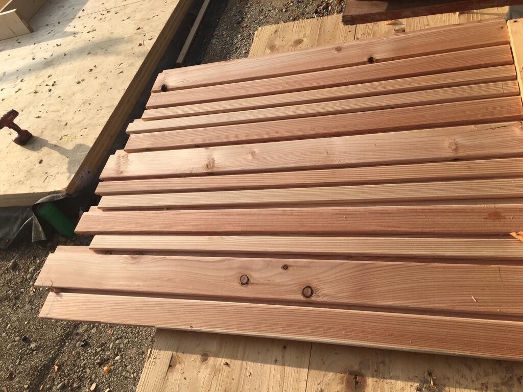Auf einer Baustelle liegen mehrere lange Holzbohlen als Rohbaustoffe gestapelt bereit.