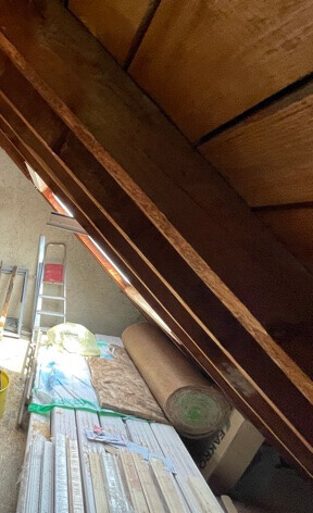 Bau-Szene mit Holzrahmen, Daemmung, Leiter und Baumaterial im Rohbau.