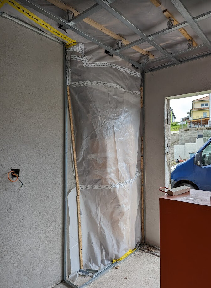 Baustelle Innenraum mit Stahlwandrahmen, Staubschutzfolie und offener Tür