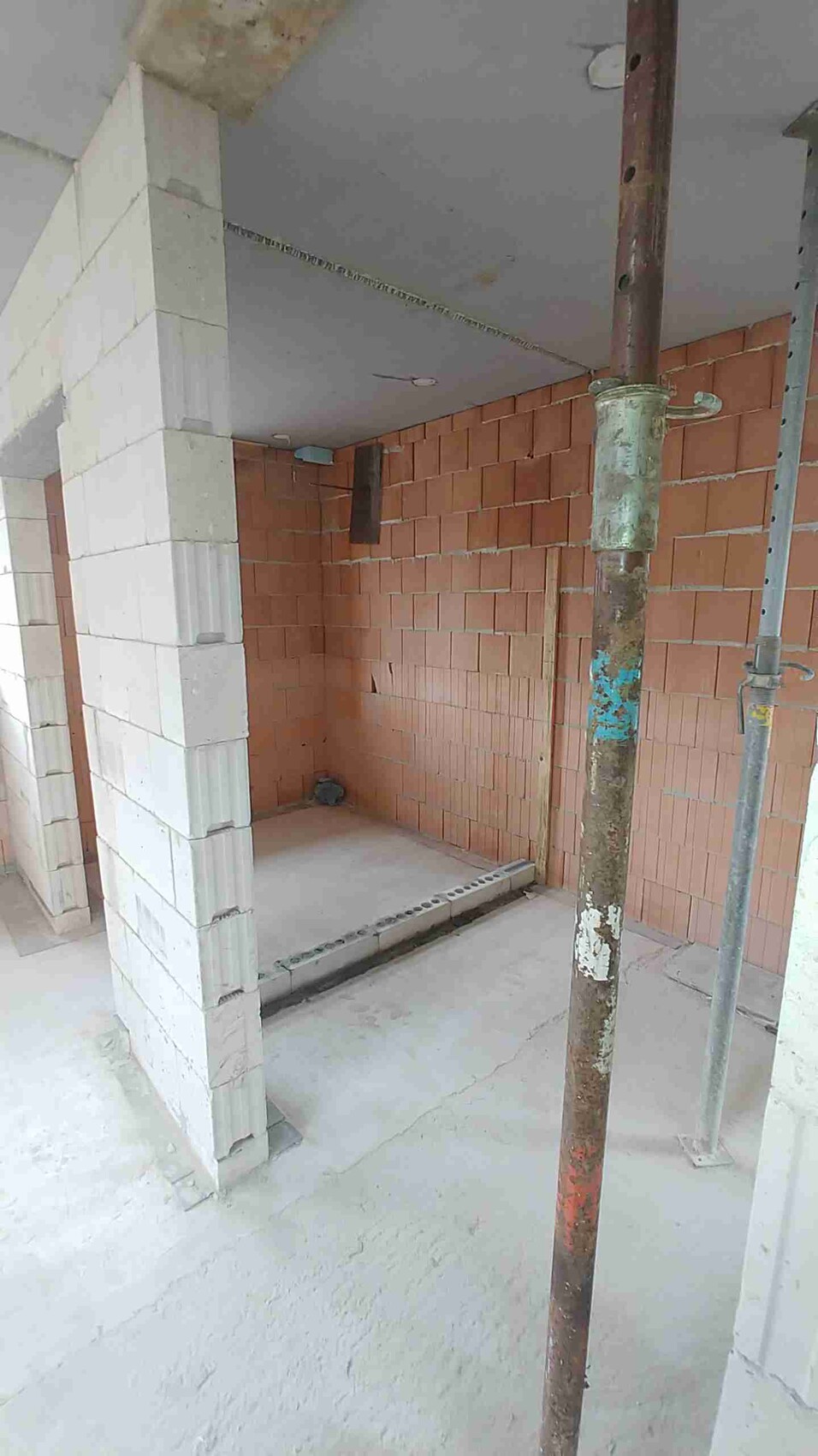 Innenraum einer Baustelle: roter Backstein, weiße Blöcke, Gerüststange