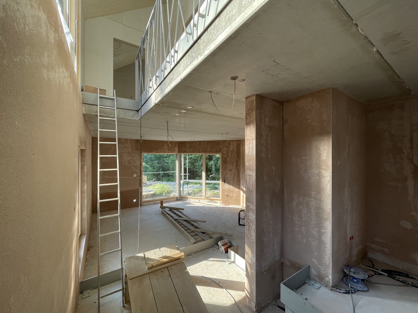 Unfertige Innenraum-Baustelle im Haus mit Betondecke, Säulen, Leiter und Baumaterial.