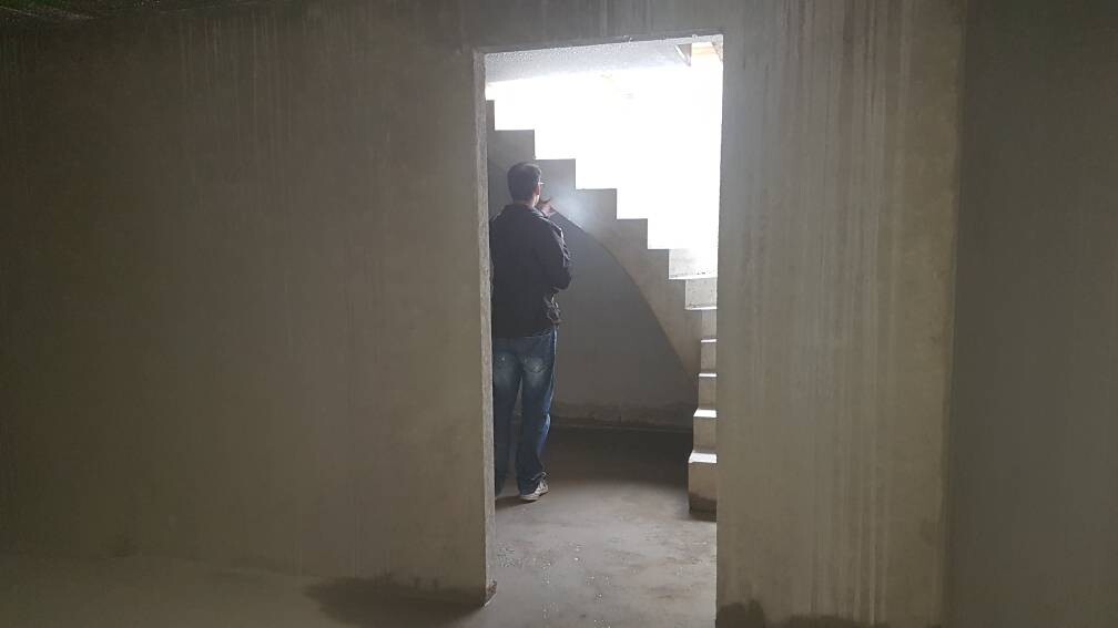 Person in unfertigem Betonrohbau, von hinten, steht neben einer halbrunden Treppe.