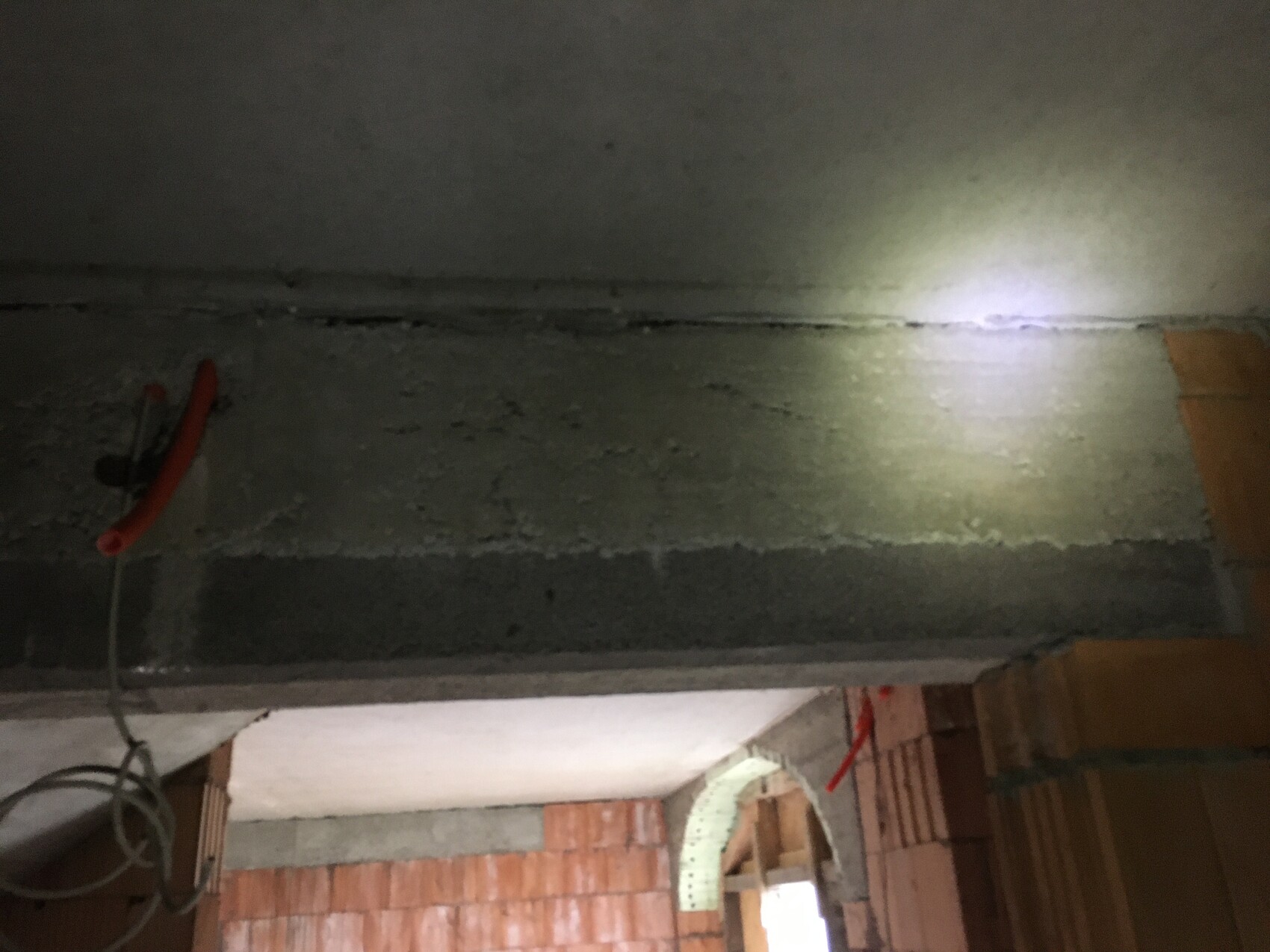 Sicht auf eine Baustelle: Betonbalken, Ziegelwände und Kabelgewirr