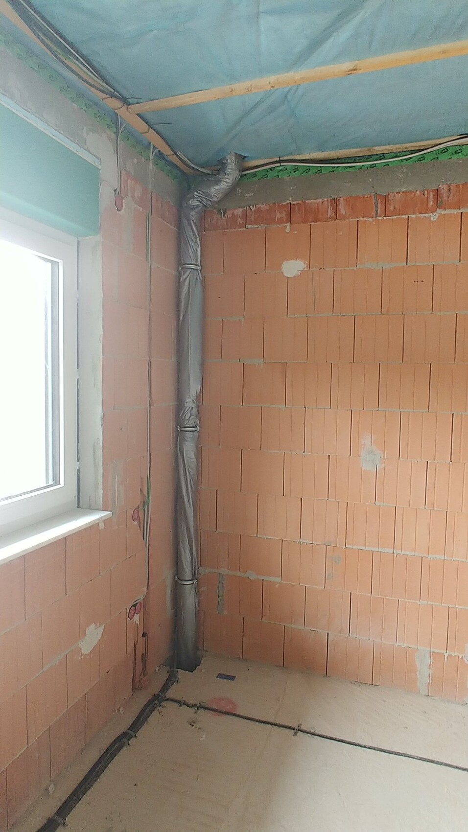 Rohbau-Innenraum mit Ziegelwänden und installierten Rohren