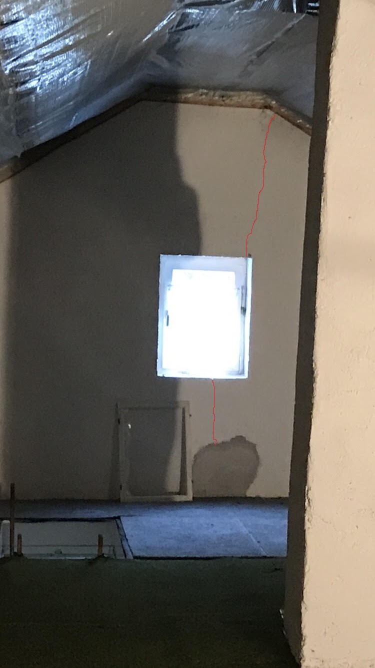 Unfertiger Innenraum mit kleinem Fenster, Rohbau und Dämmung sichtbar.