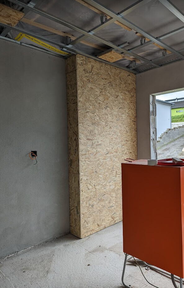 Baustelle: OSB-Pfeiler, freiliegende Deckenkonstruktion, roter Schrank im Vordergrund