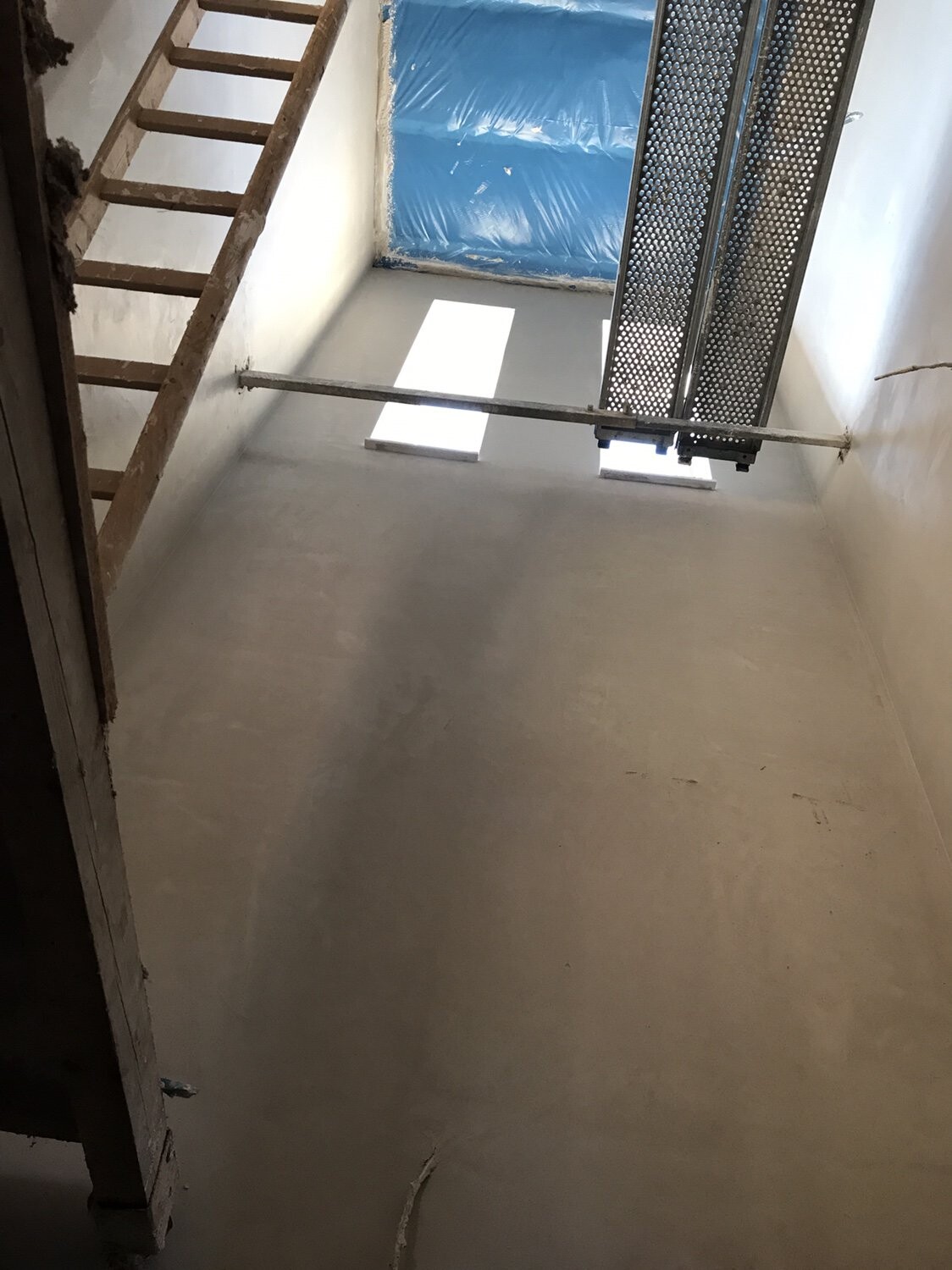 Unfertiger Innenbaubereich mit Treppe links und Metallplattform rechts.