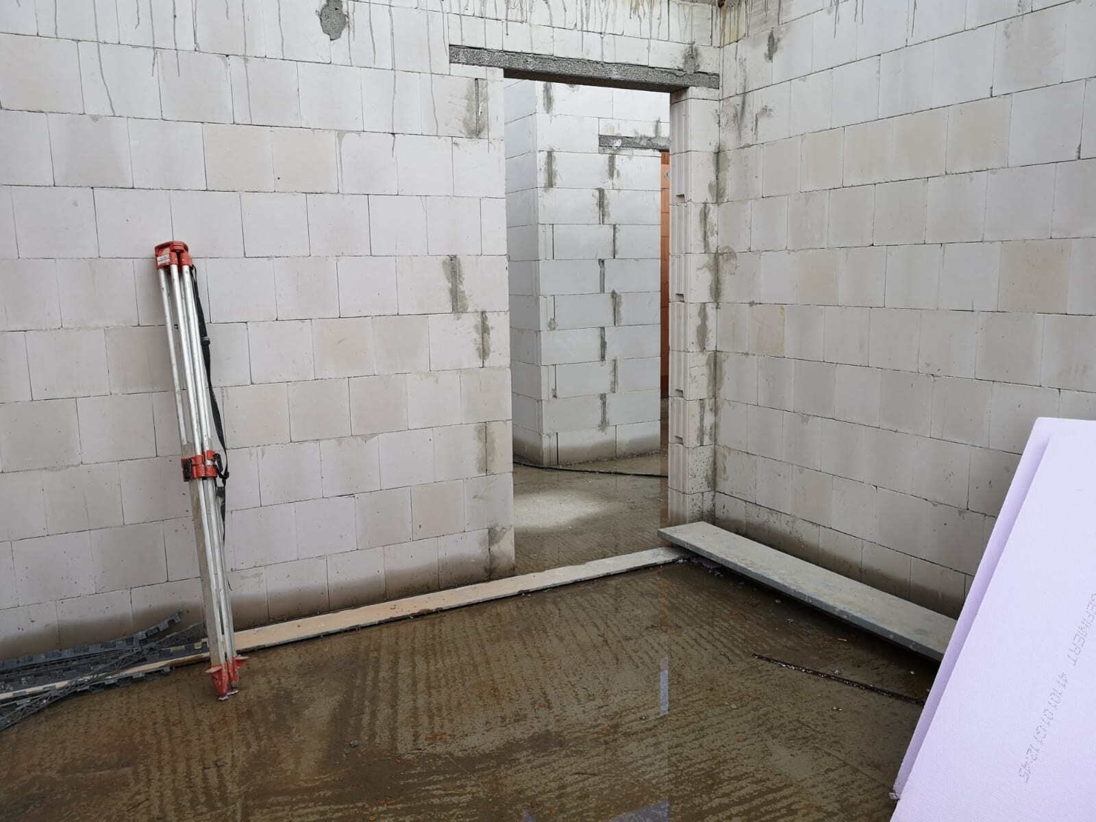 Baustelle: Innenraum mit weißen Blockwänden, Leiter links, offener Durchgang ins nächste Zimmer