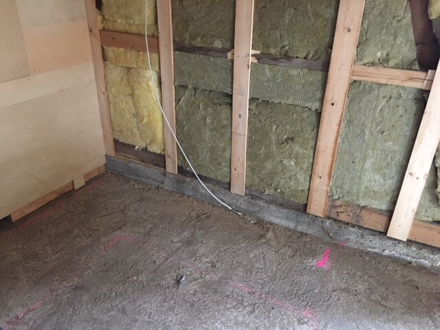 Unfertiger Innenraum-Rohbau mit Holzrahmen und Dämmung