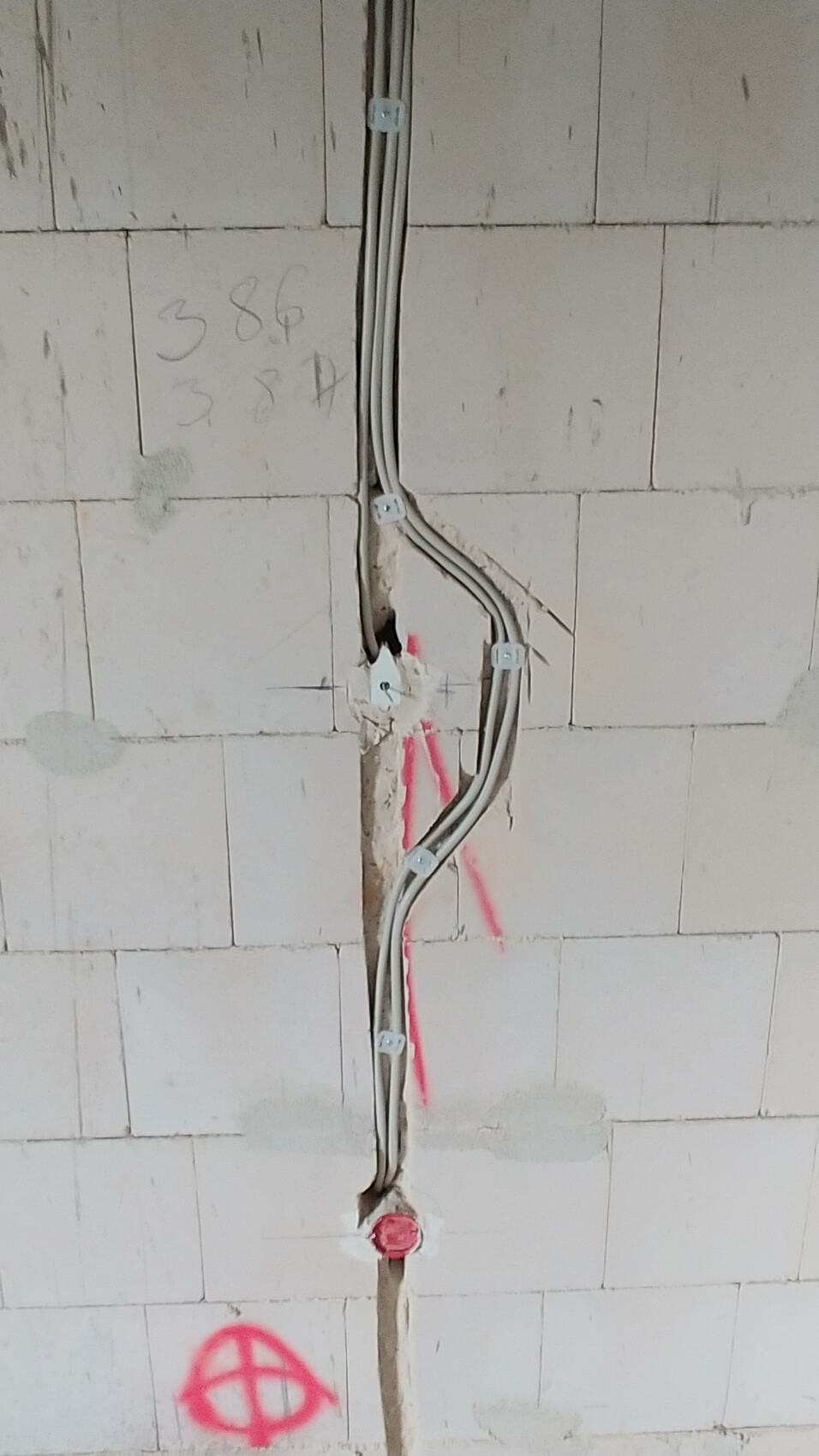 Unverkleidete Wand mit sichtbaren Elektroleitungen im Rohbau