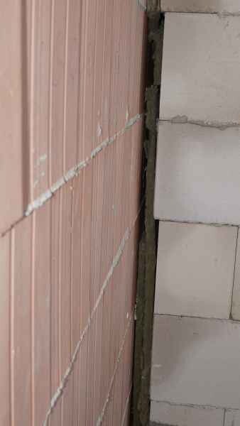 Baustellenkante zwischen Ziegelwand und Betonwand mit Spalt