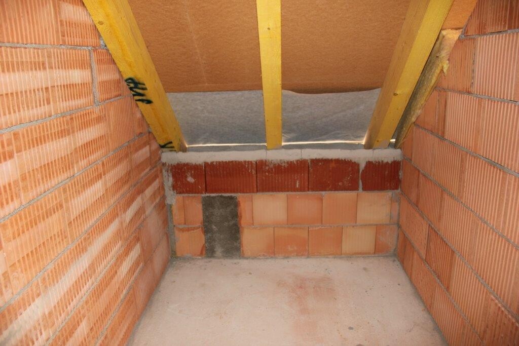 Unverputzter Keller-Rohbau mit Ziegelwänden, Holzbalken-Dachkonstruktion und Betonboden.