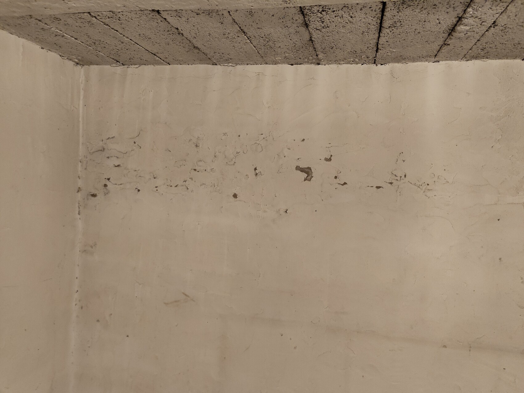 Unverputzte Kellerwand im Rohbau mit Rissen und grober Mauerwerksoberfläche