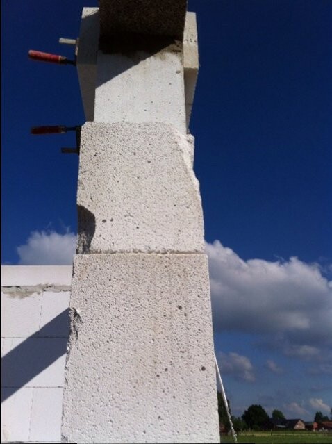 Beton-Saeule im Rohbau mit Bewehrungstangen gegen blauen Himmel
