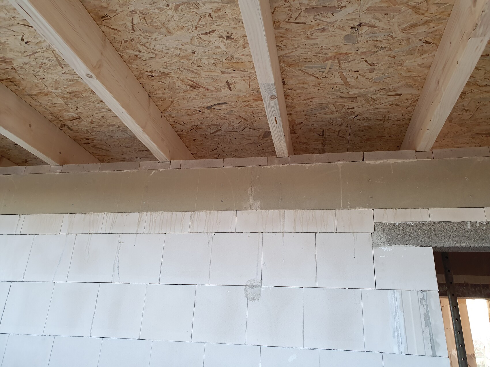 Rohbau: Holz-Dachstuhl, OSB-Deckenverkleidung über Betonblockwand.