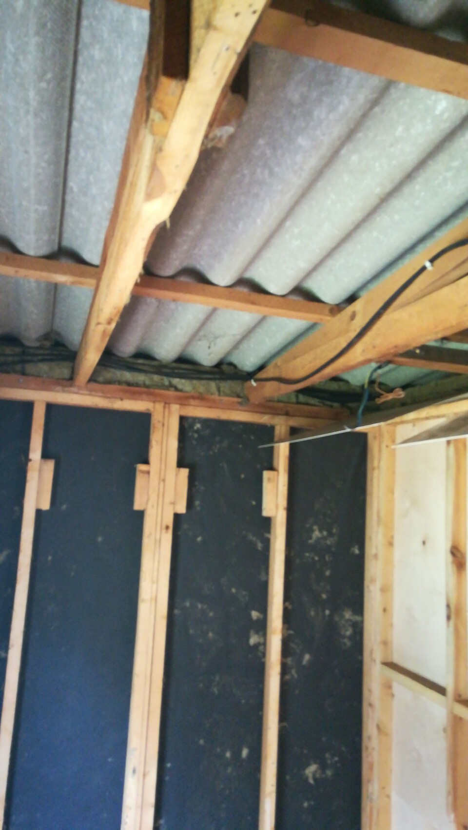Rohbau-Innenraum mit Holzrahmen, Dachträgern und sichtbaren Kabeln