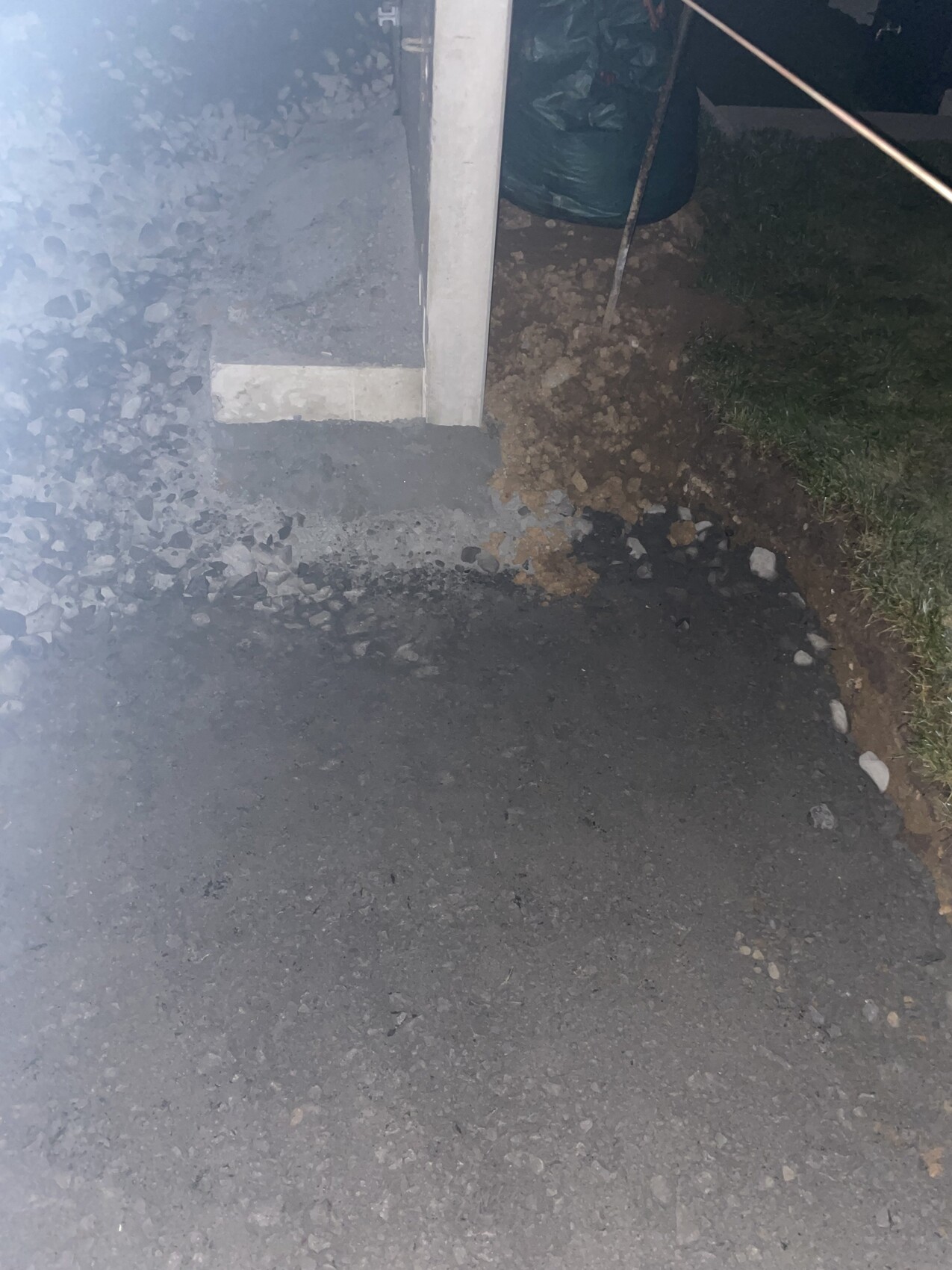 Außenbereich einer Baustelle mit Betonfundament, Kies und Gras daneben