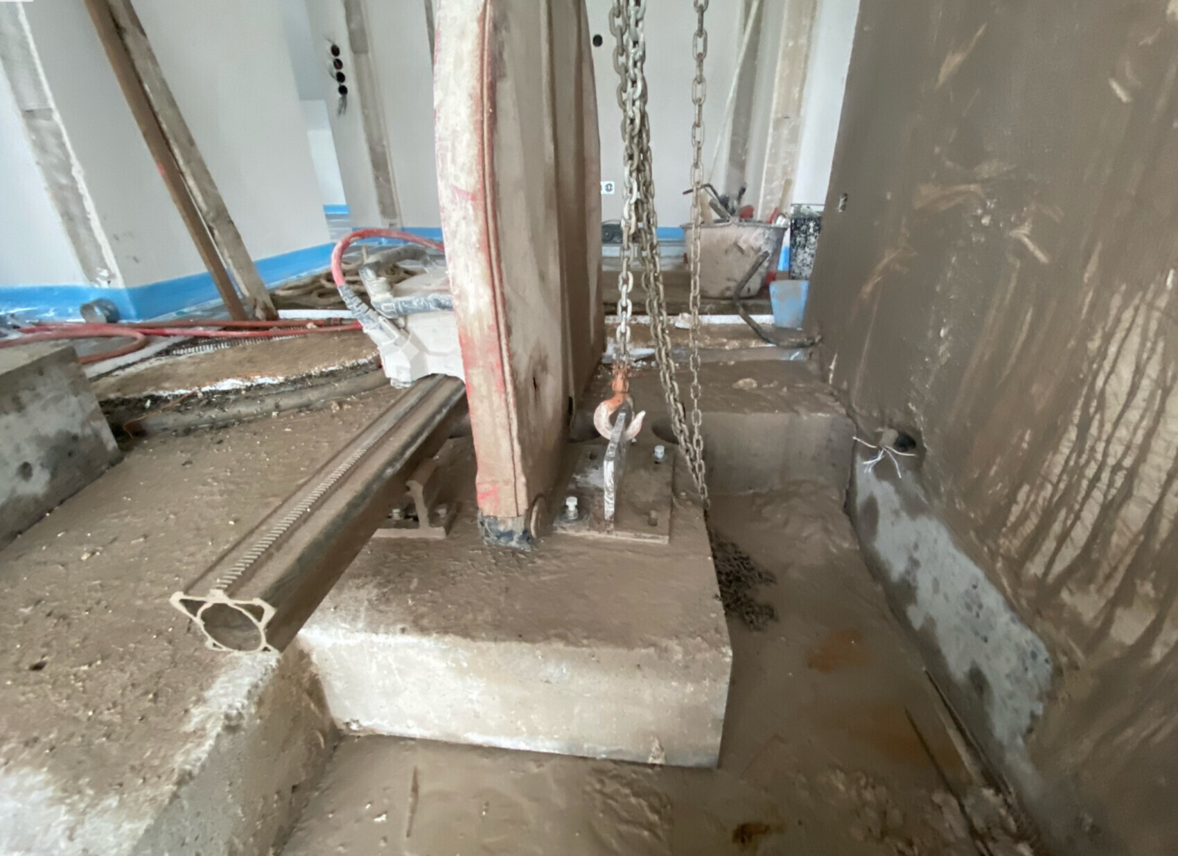 Baustelle mit Betonfundament, Stahlträger, Kettenzug und Rohbauarbeiten