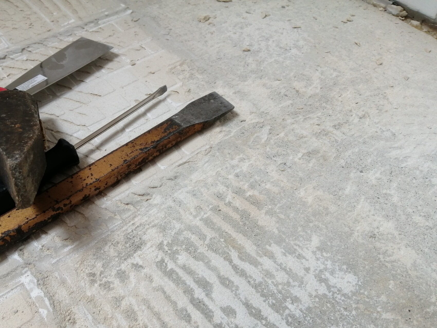 Baustelle mit Kelle, Meißel und rostigem Werkzeug auf staubigem Boden