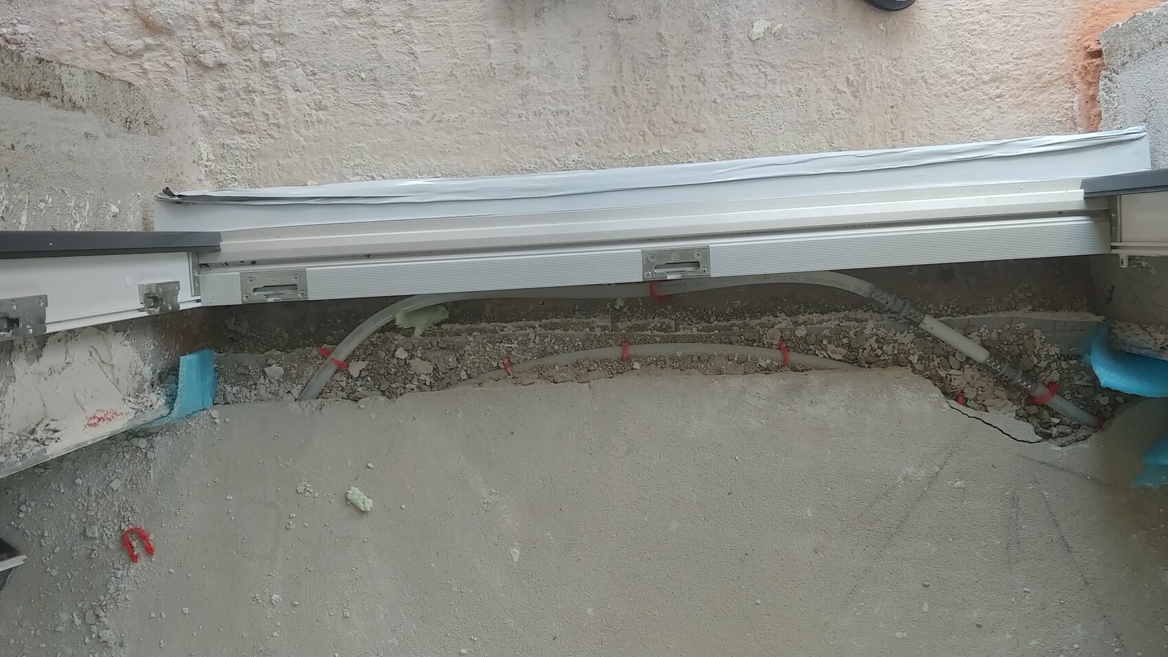 Außenbaustelle mit Fundamentgrube, Rohren, Metallprofilen und Erdreich