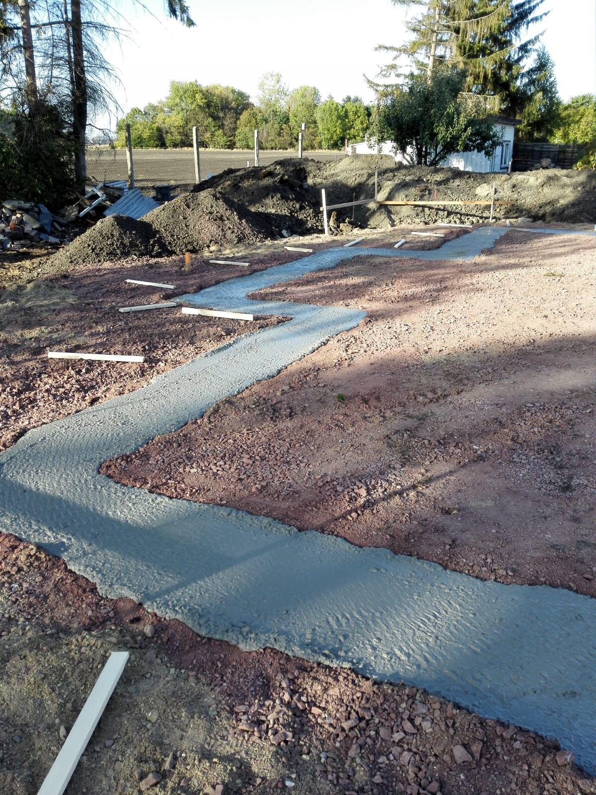 Frisch gegossene Betonfundamente auf Baufläche mit Erdarbeiten