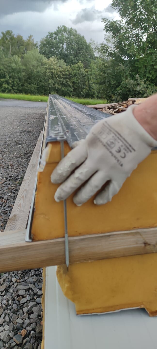 Hand mit Arbeitshandschuh befestigt Draht an gelber Bauform auf Baustelle