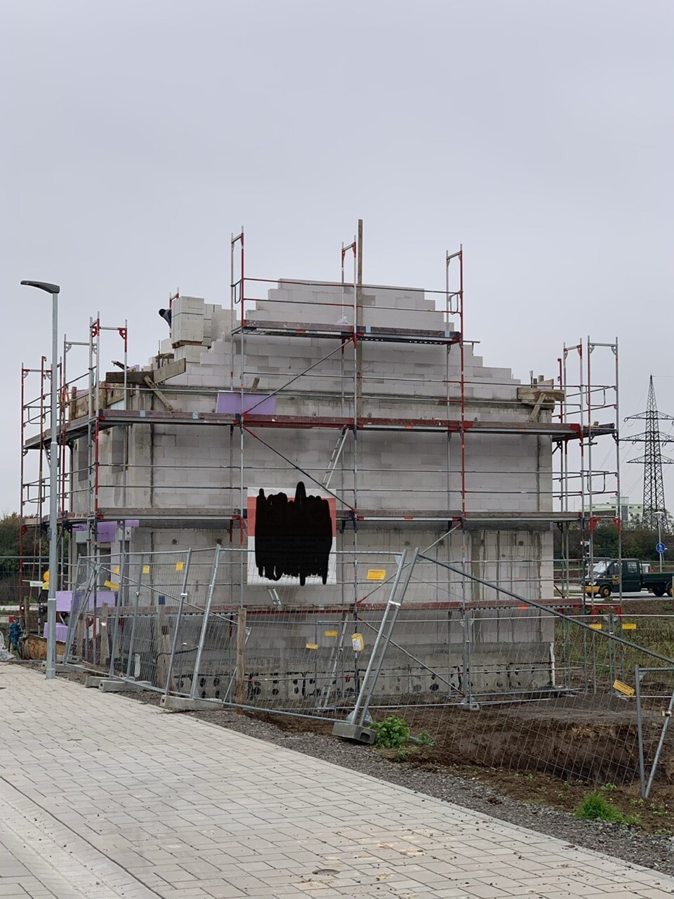 Baustellengebäude aus Beton mit Gerüst, Bauzaun und sichtbaren Bauarbeiten.