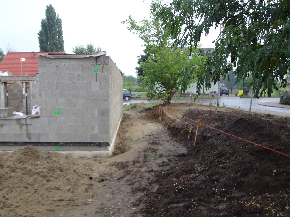 Kleines Rohbau-Gebäudeteil aus Betonblöcken auf einer Baustelle mit Erdarbeiten