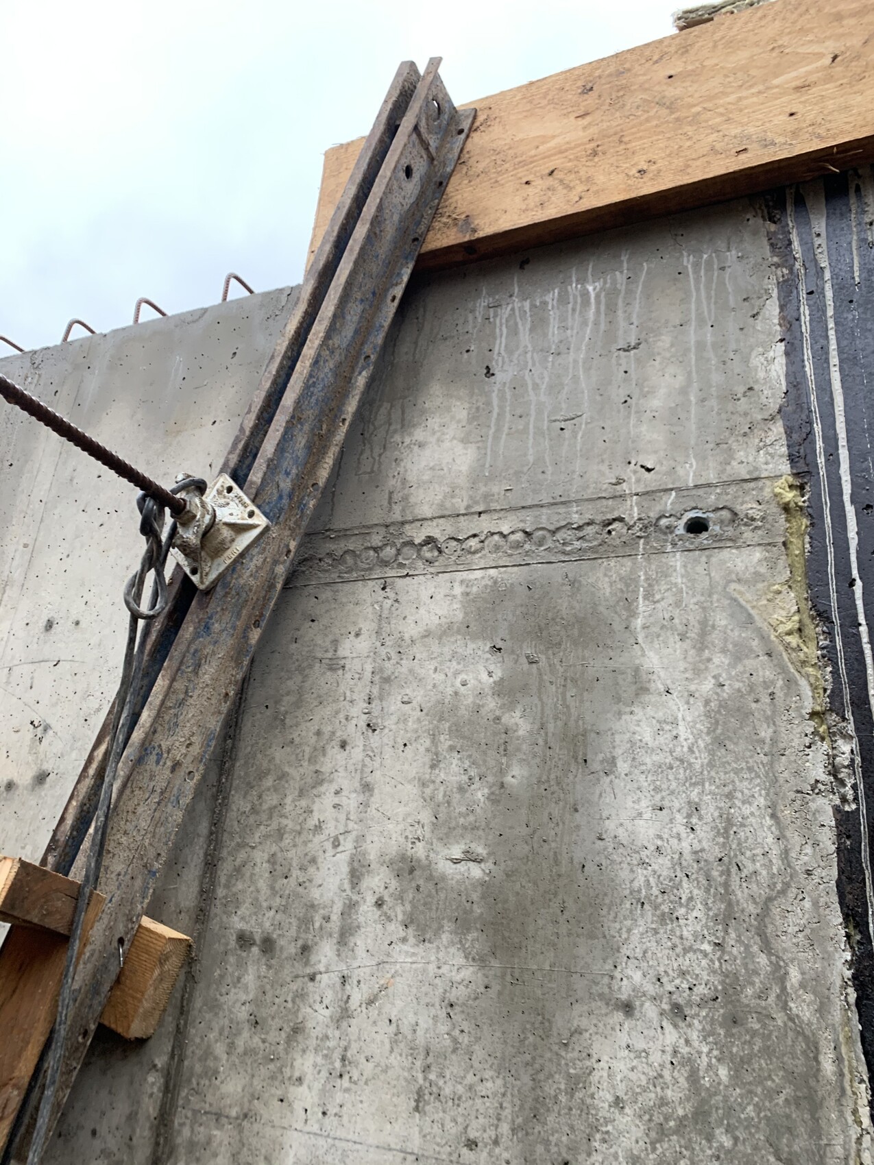 Sicht auf eine Betonwand mit Holzform, Bewehrung und Drahtseil auf einer Baustelle