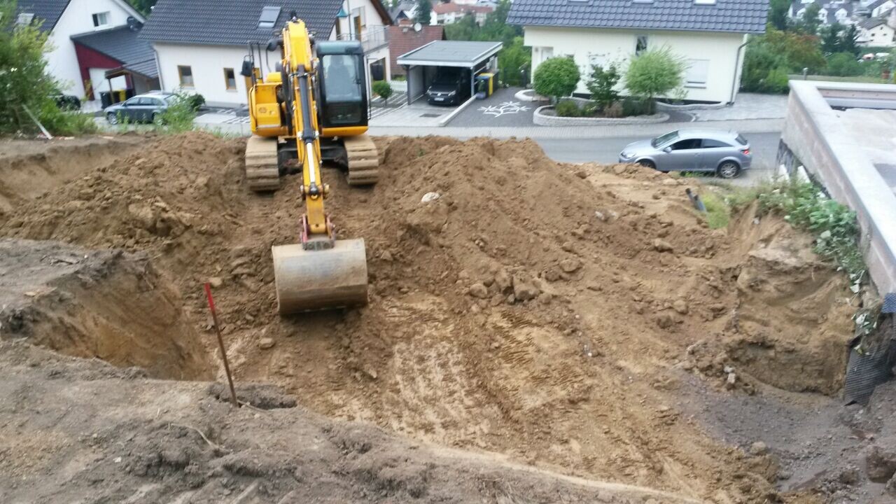 Bagger gräbt Baugrube für Rohbaufundament in Wohngegend