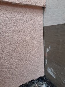 Außenwand Ecke mit rauem Putz und sichtbarem Fundament