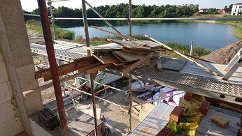 Baustelle mit Gerüst, Holzbauteile und Rohbauarbeiten am Ufer eines Sees
