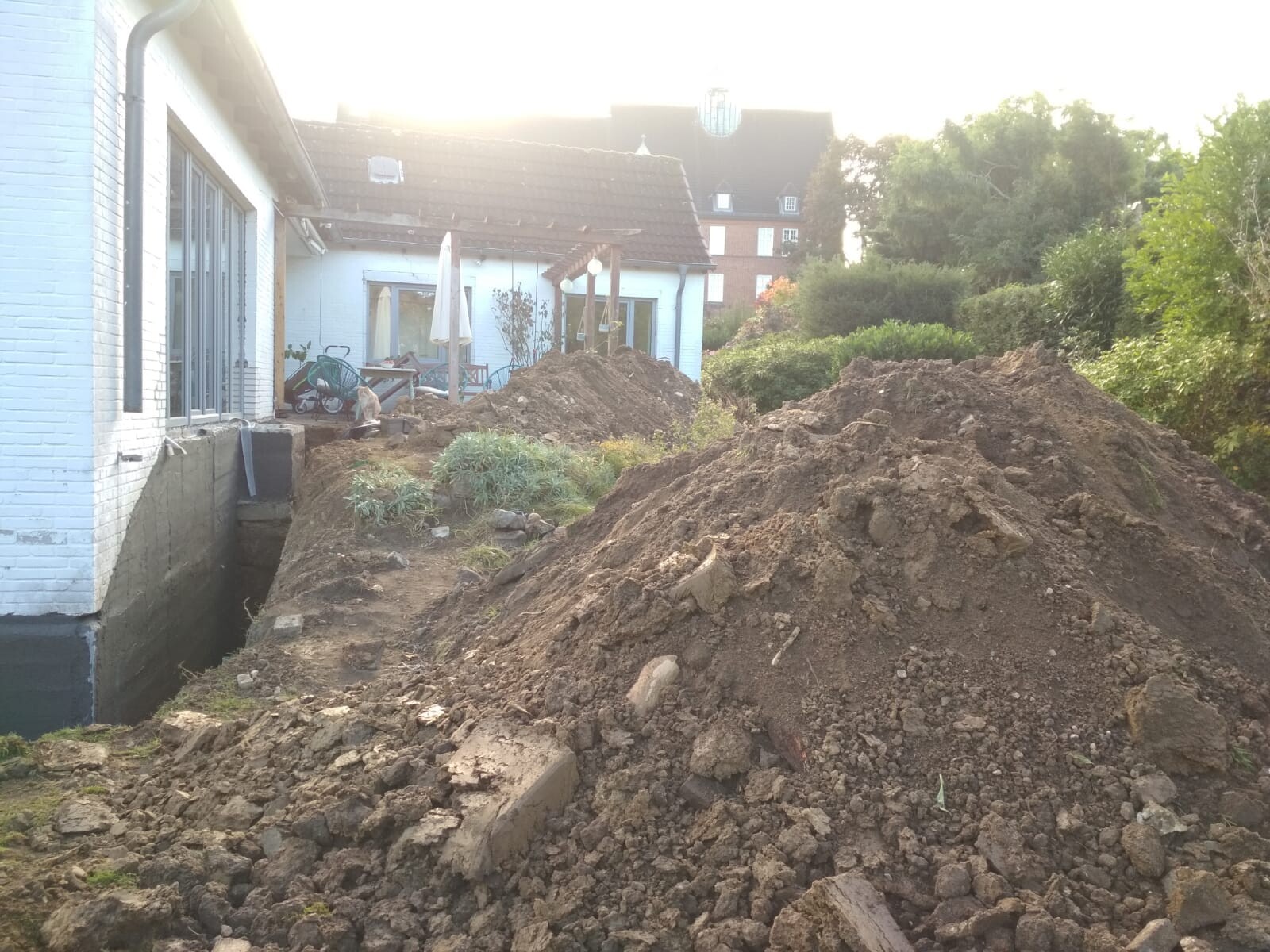 Gartenbaustelle mit Erdmassen und Baugrube neben Wohnhaus