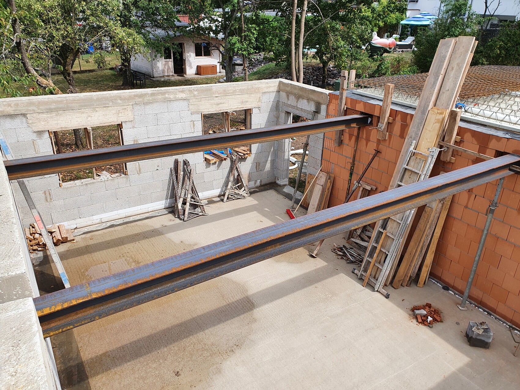 Rohbau-Innenraum mit Stahlträgern, Betonwänden und Holzbalken auf Baustelle