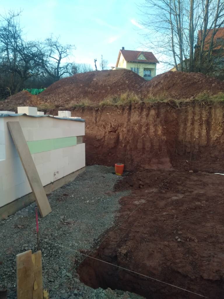 Baustelle mit Baugrube, Fundamentarbeiten und Baumaterialien